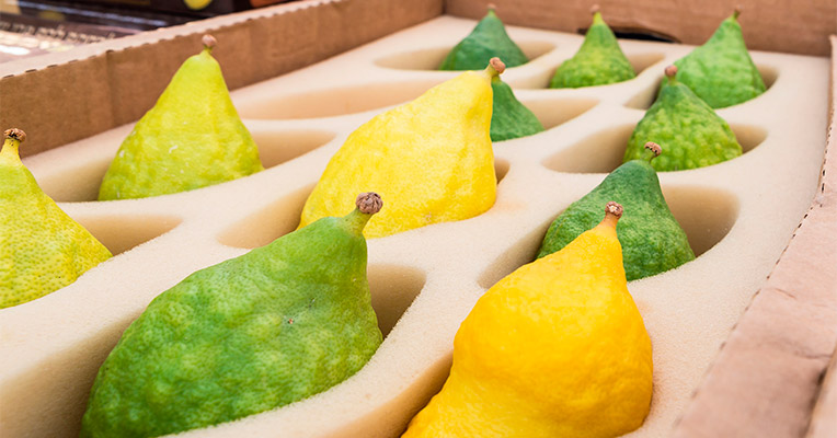 Зеленые и желтые плоды цитрона в коробке