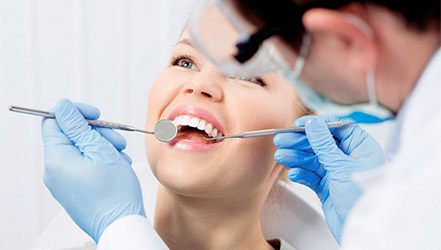 Стоматолог осматривает зубы пациентки