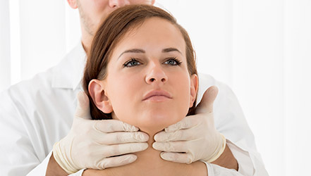 Доктор обследует щитовидку женщины