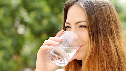 Счастливая женщина пьет воду