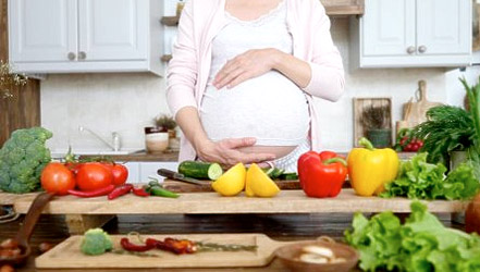Беременная девушка делает салат из болгарского перца и других овощей