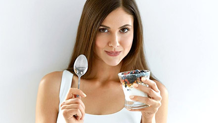 Красивая девушка ест ежевику с йогуртом