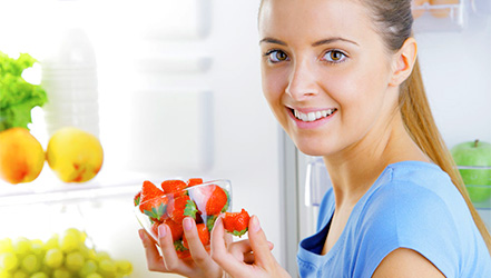 Девушка хранит клубнику в холодильнике