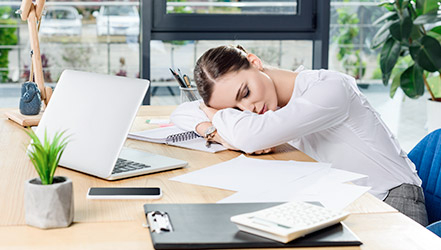 Уставшая девушка спит на рабочем месте из-за нехватки железа