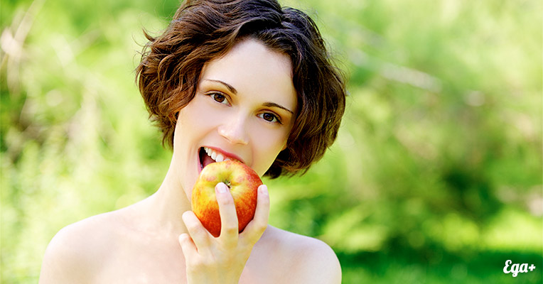 Красивая девушка ест яблоко